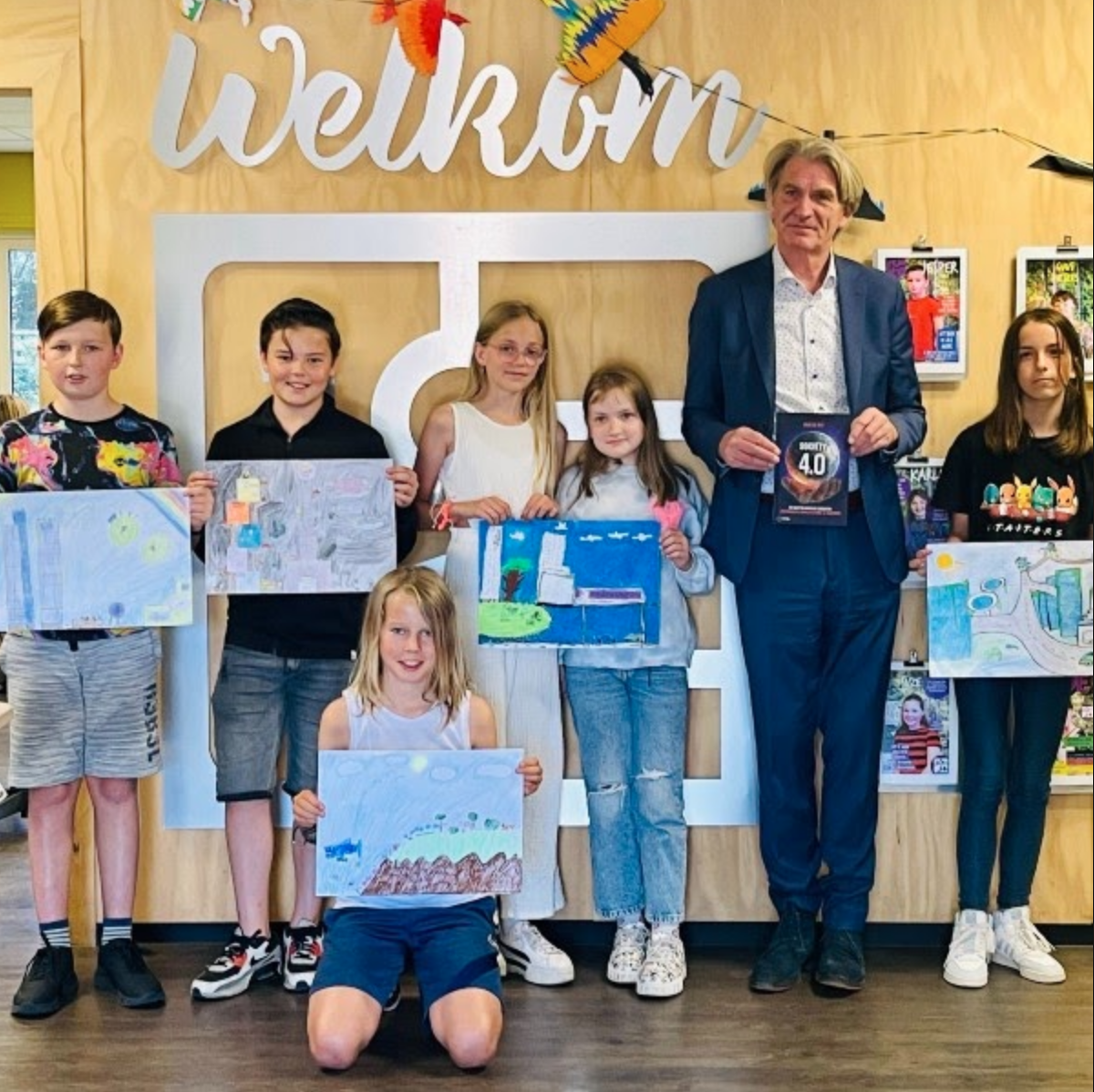Bob de Wit met schoolkinderen en hun tekeningen over de toekomst